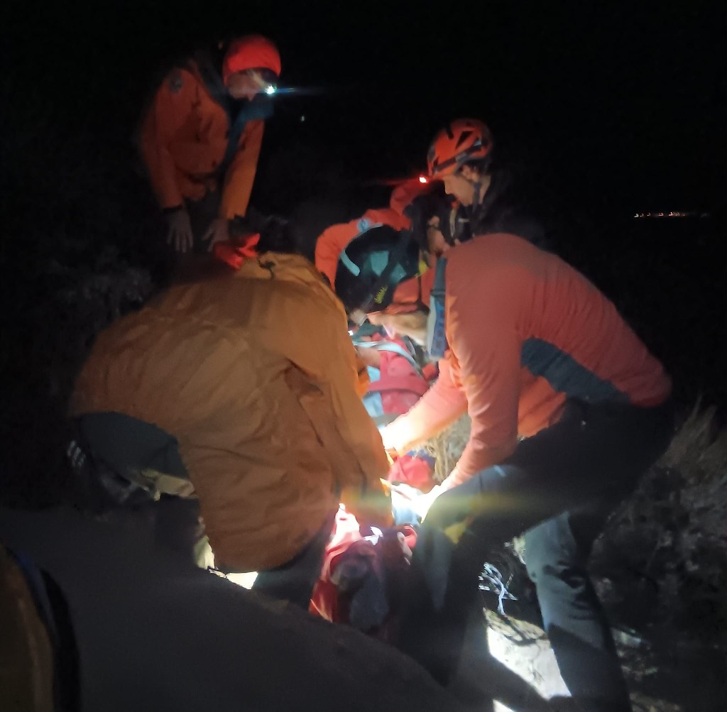 Volunteer rescue team members assist injured hiker at night 