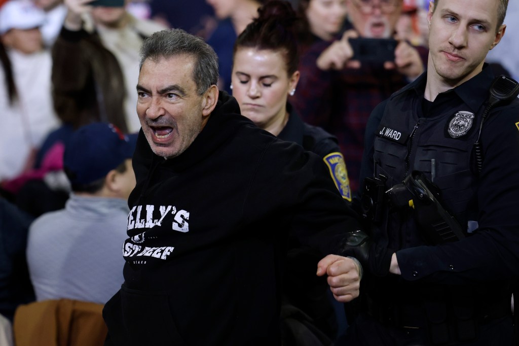 A protester is ejected by police from a campaign rally with Republican presidential candidate and former President Donald Trump at the SNHU Arena on January 20, 2024 in Manchester, New Hampshire.