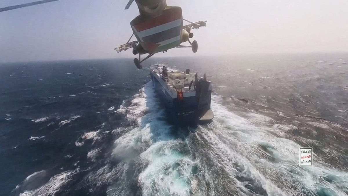 Houthi military helicopter near a commercial ship