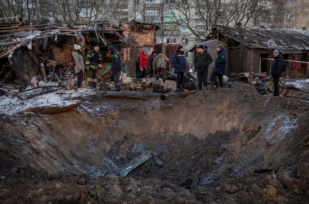Local residents look at a crater near their residential building damaged during a Russian missile strike, amid Russia's attack on Ukraine, in the town of Shostka, Sumy region Ukraine on Jan. 13, 2024.