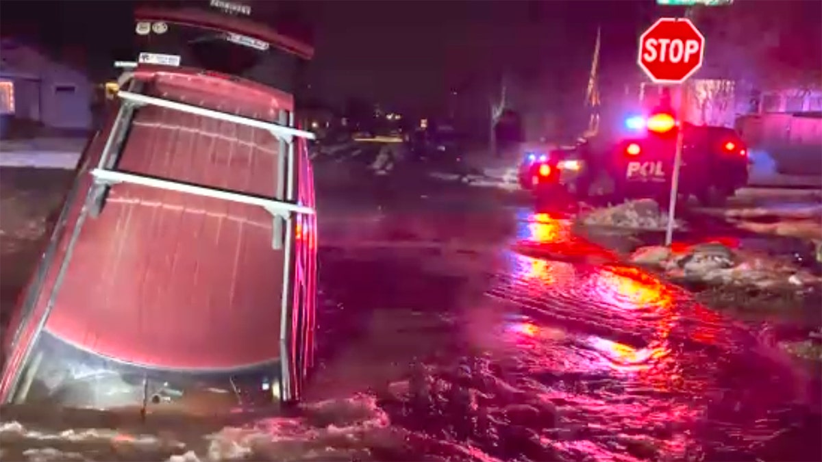 Red SUV sticking out of a giant sinkhole