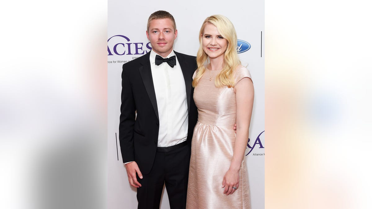 Elizabeth Smart in a satin pink dress next to her husband in a suit and bow tie