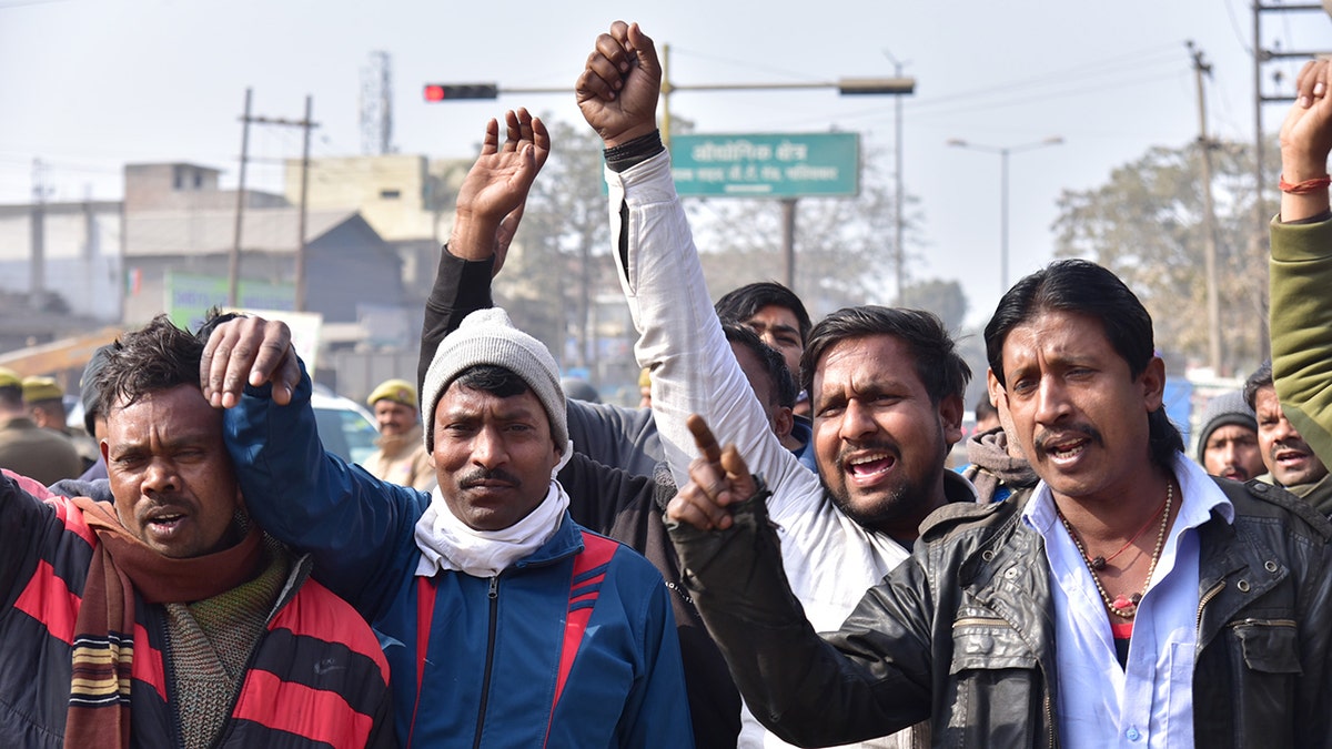 Male Indian protestors raise hands in the air, protesting over new hit-and-run law