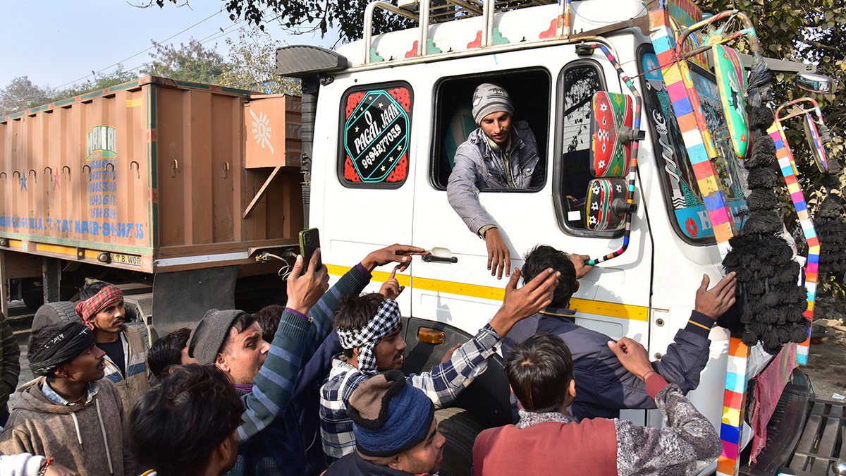 Male Indian protestors reach out to bus driver on the street during protest over new hit-and-run law