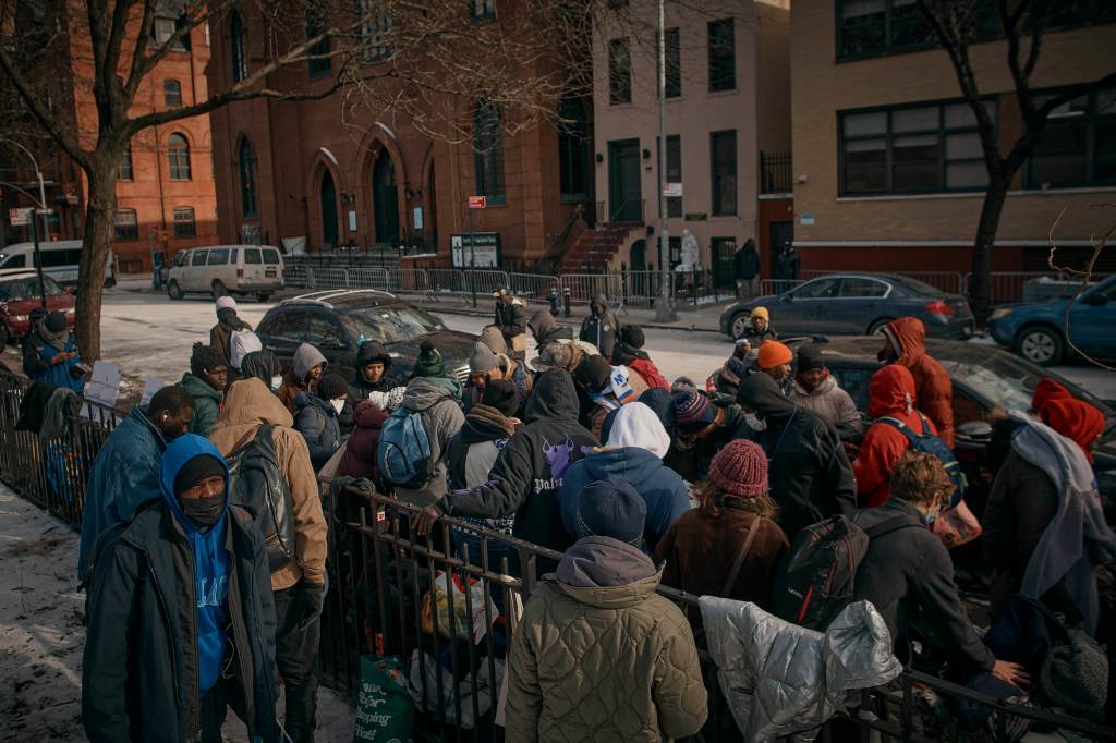 Migrants pick up clothes as mutual aid groups distribute food and clothes under cold weather near the Migrant Assistance Center at St. Brigid Elementary School, on Saturday, Jan. 20, 2024, in New York. 