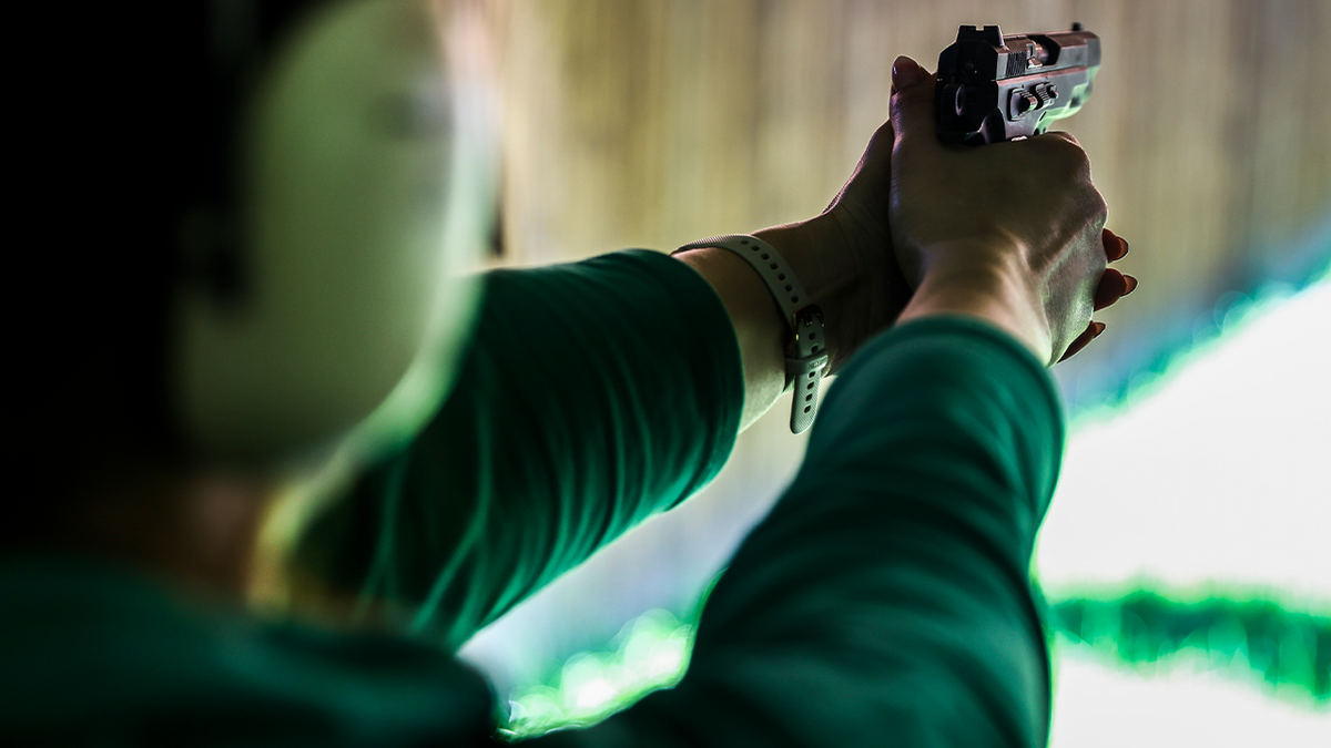 Woman aiming gun at range