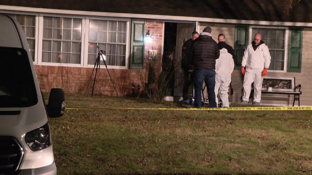 Police stand outside the crime scene at a home in Middletown Township