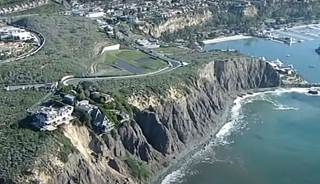 The homes are seen teetering off the edge of the cliff after the recent landslide that eroded land encompassed around it. 