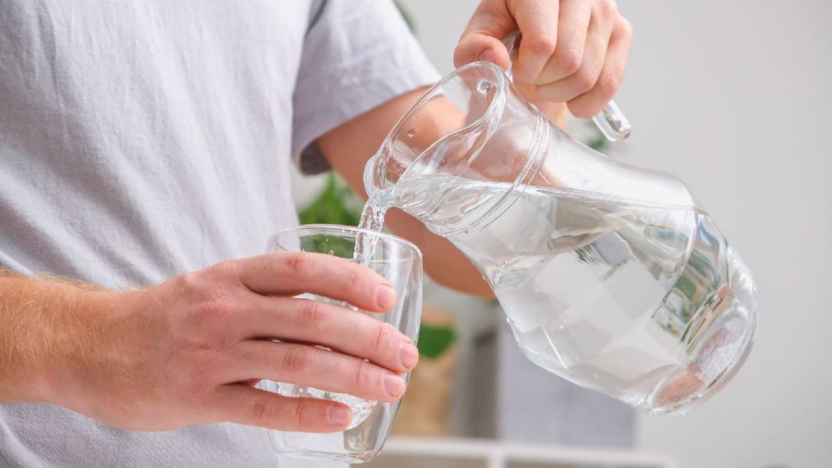 A man pours cold water into a glass.