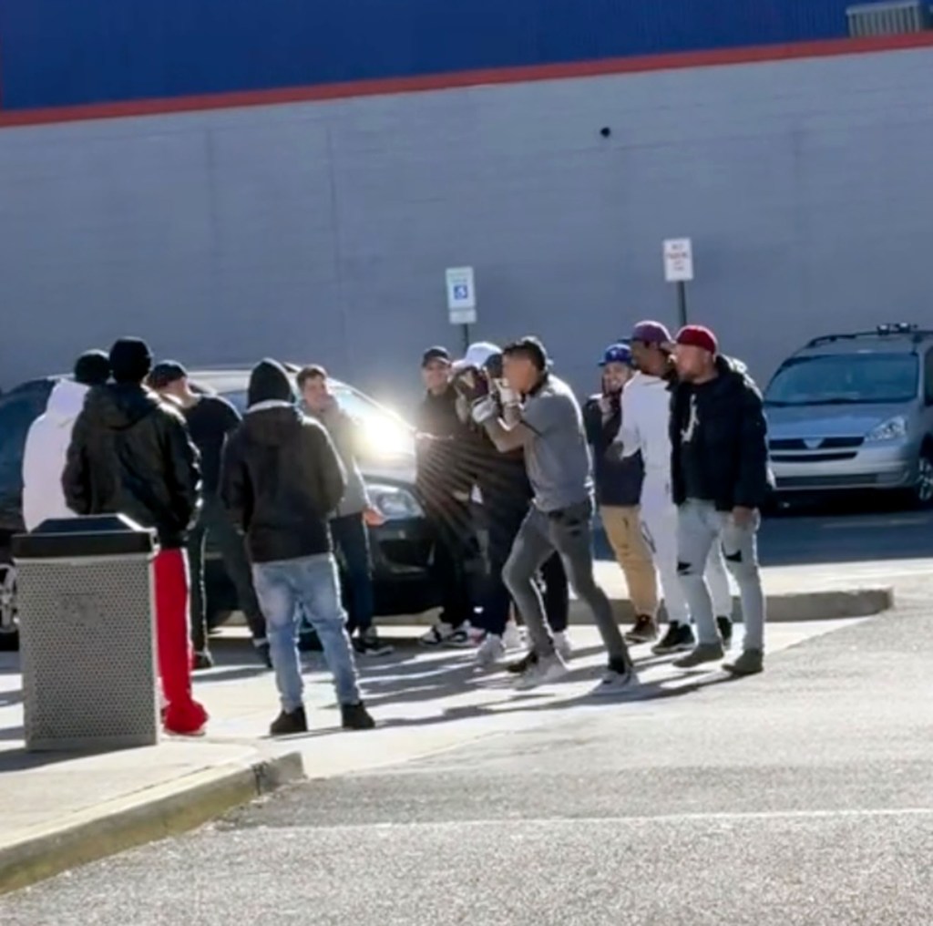 A still from a TikTok video showing a group of migrants in a McDonald's parking lot with a pair boxing