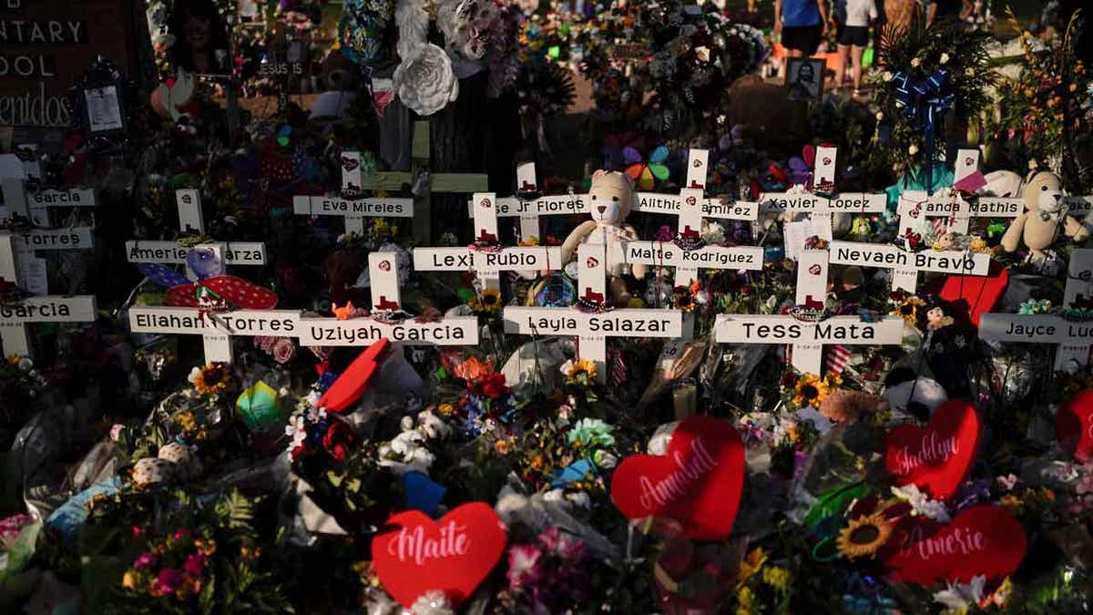 FLowers around crosses with naems of Uvalde shooting victims