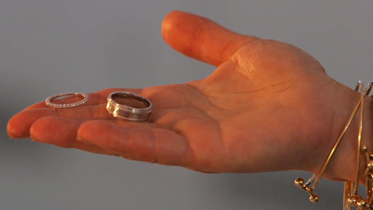 A hand holding wedding rings