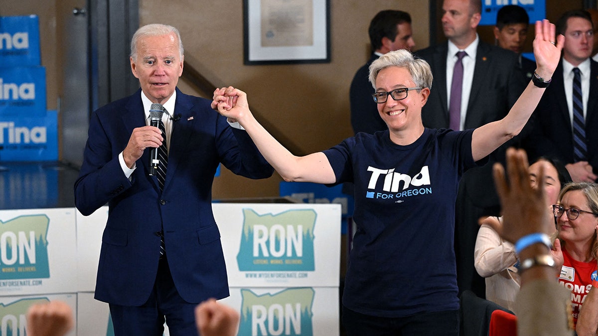 President Joe Biden holds Oregon gubernatorial candidate Tina Kotek's hand at an event